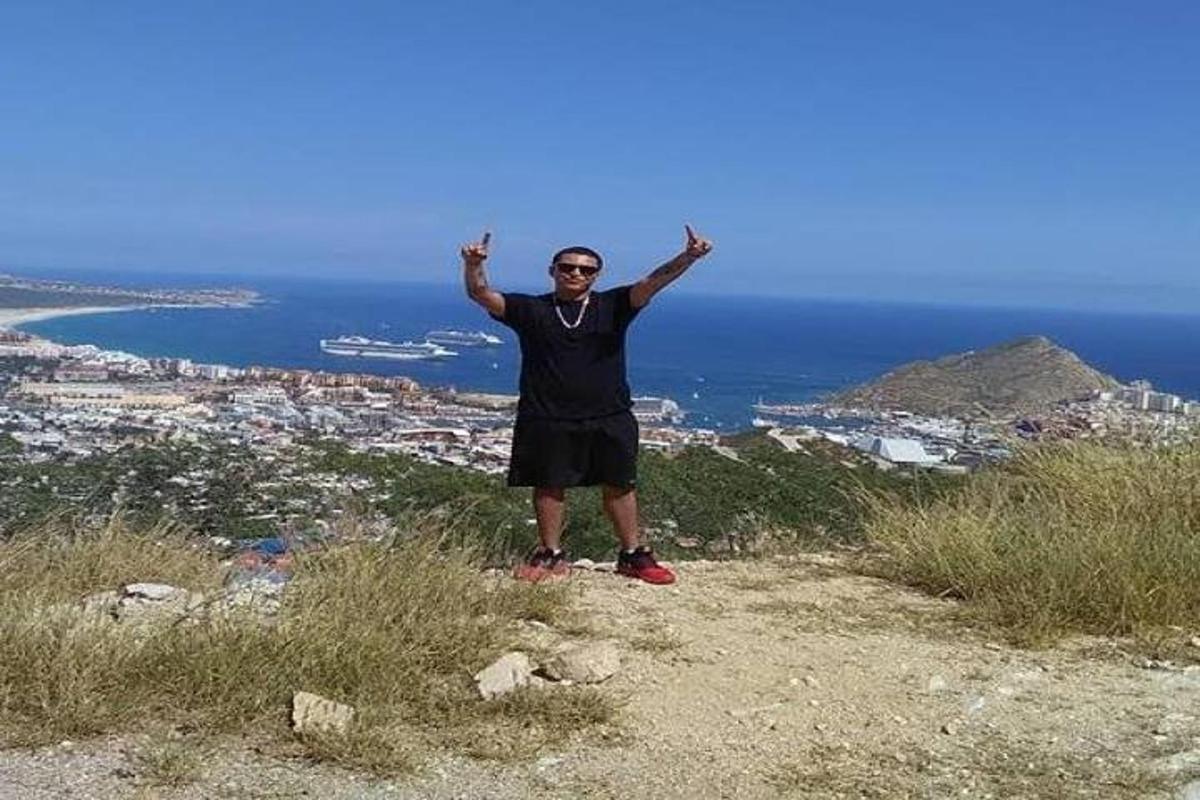 muž stojící na vrcholu kopce se zdviženýma rukama