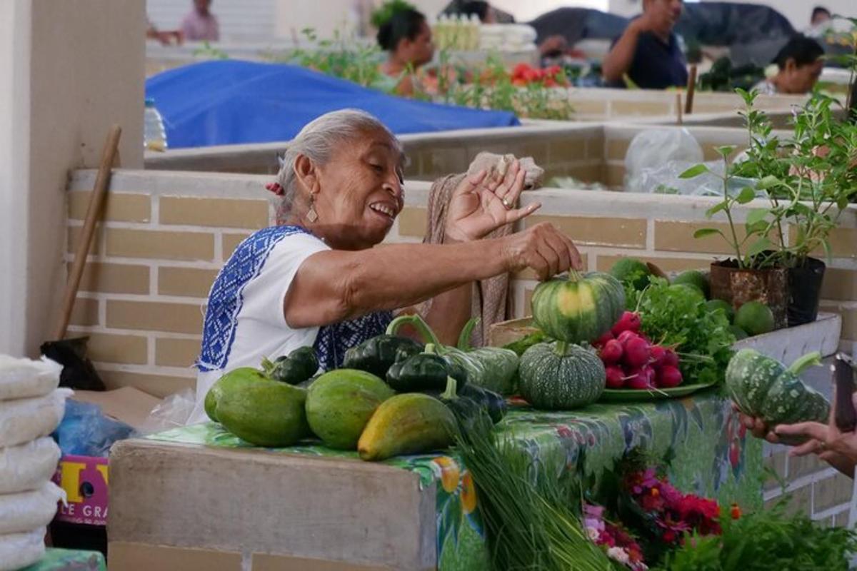 una donna anziana seduta a un tavolo con frutta e verdura
