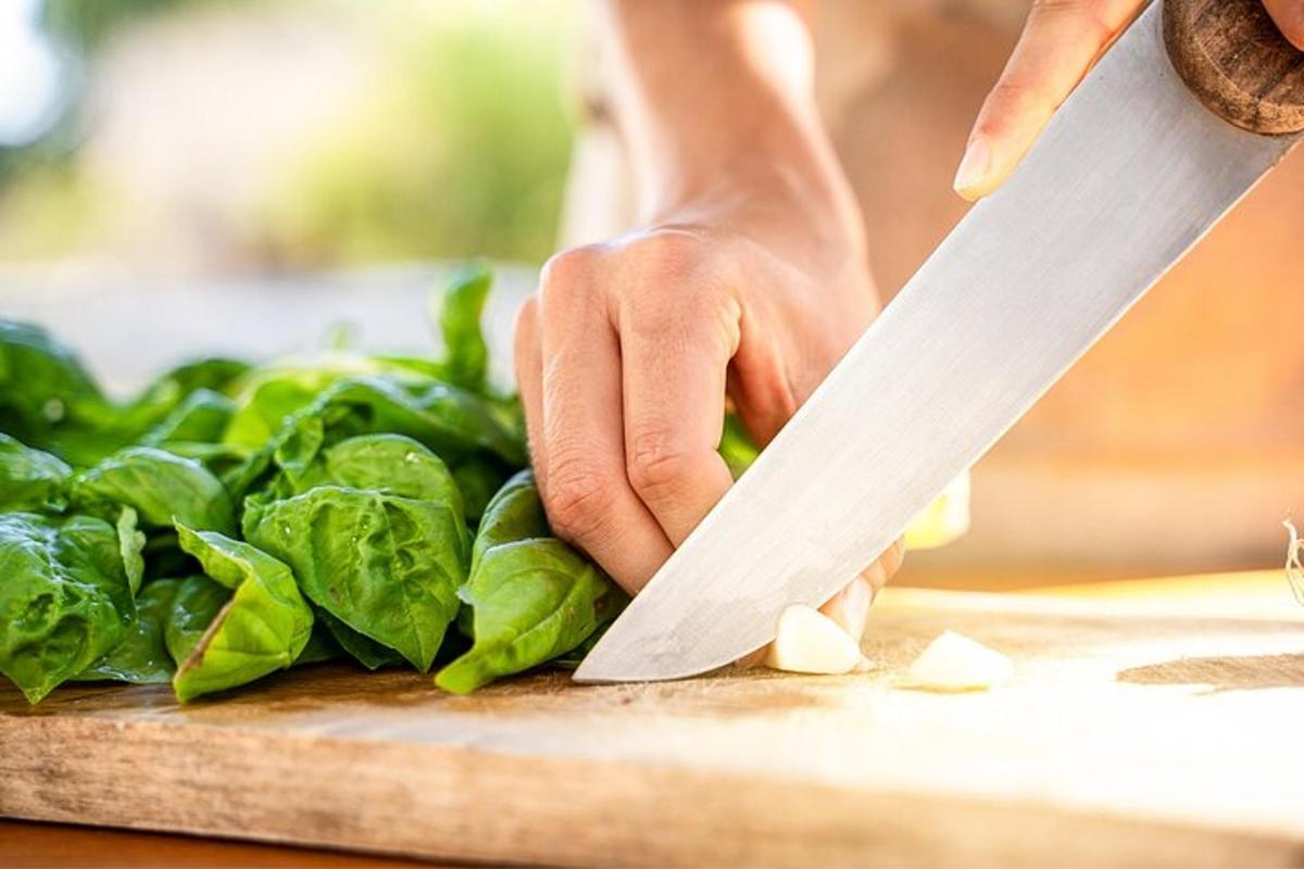 henkilö leikkaa pinaattia leikkuulaudalla veitsellä
