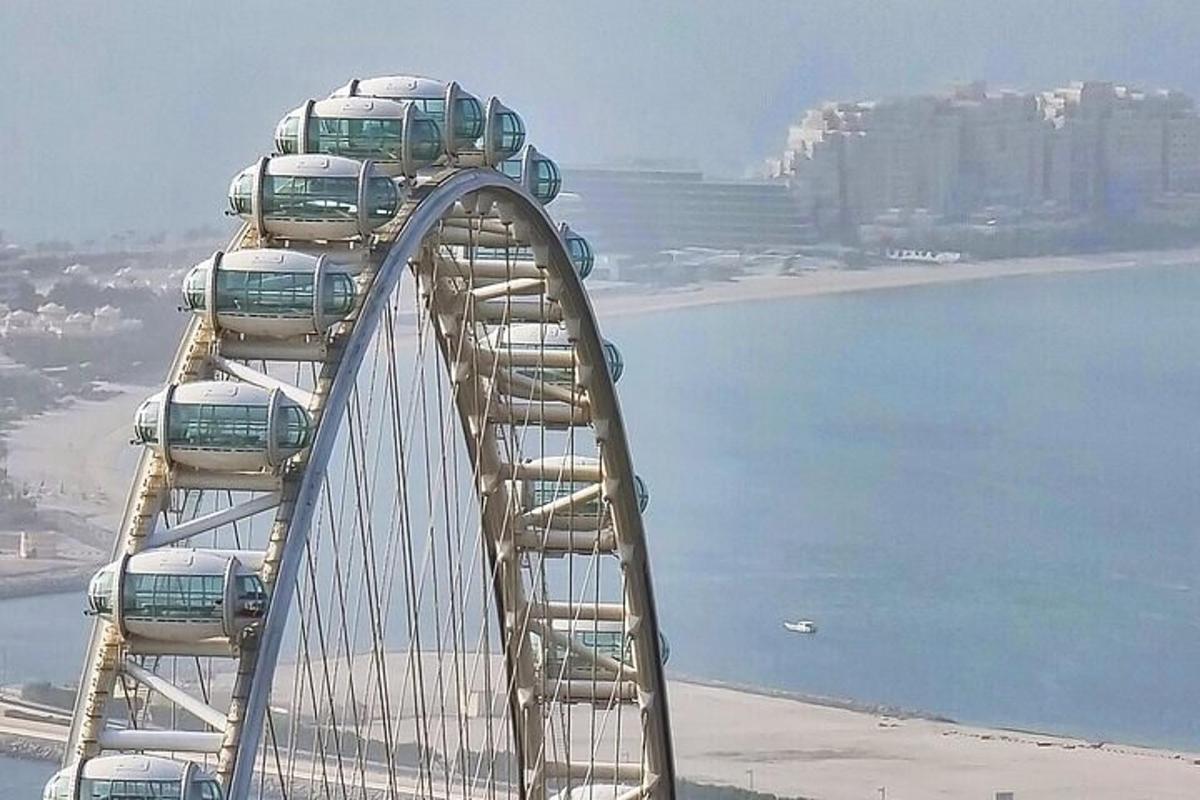 a ferris wheel with cars on it next to the water
