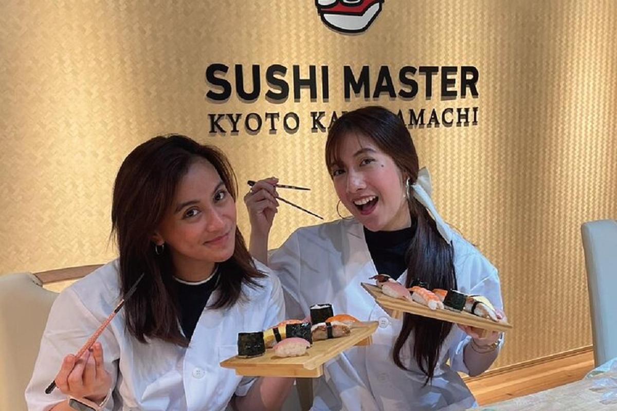 dua wanita memegang dua piring sushi master