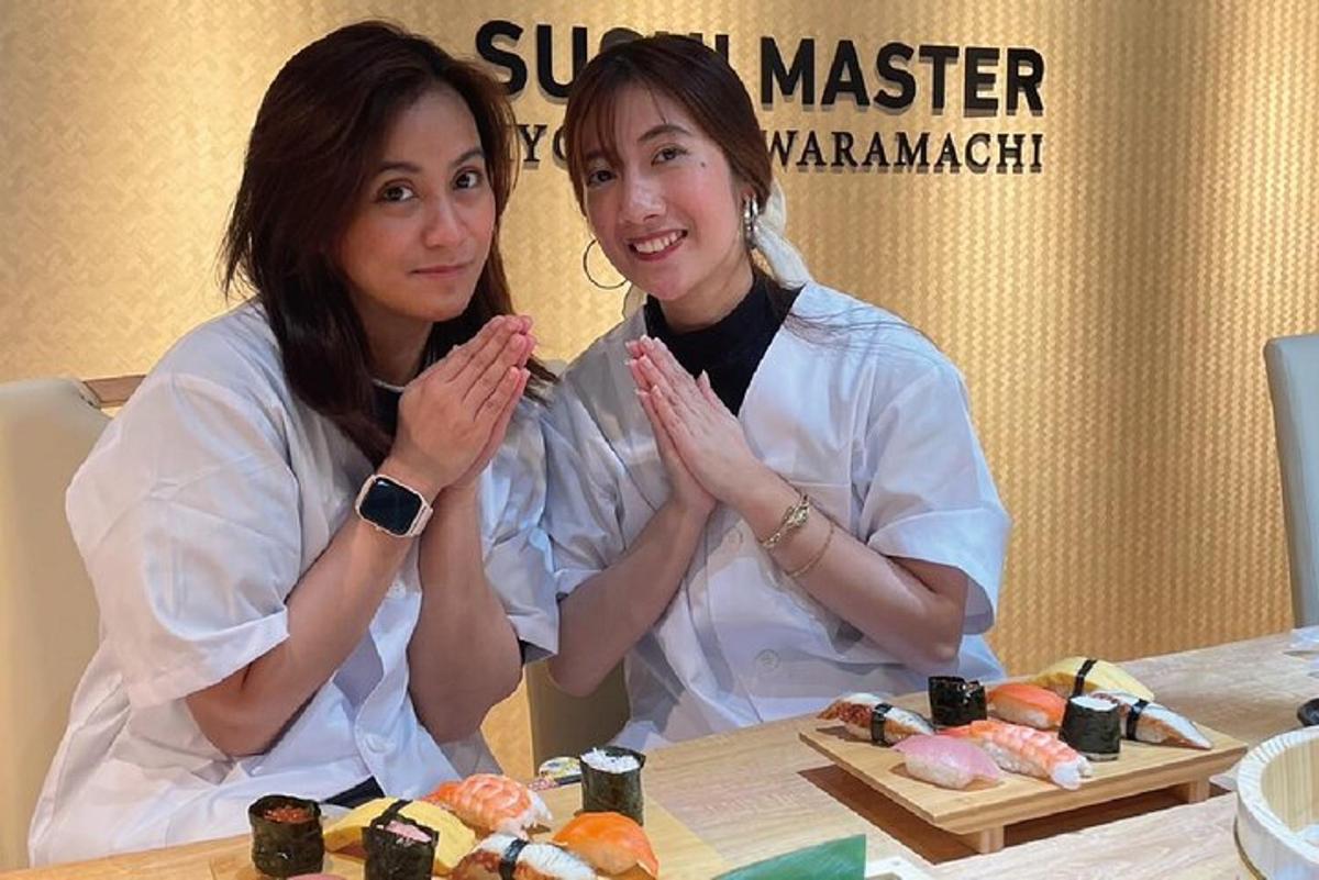 dua wanita sedang duduk di meja dengan sushi