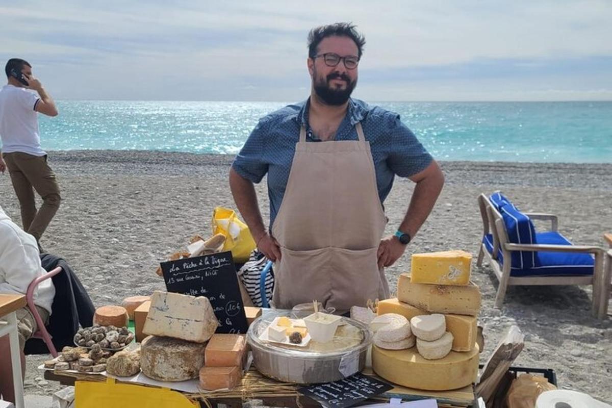 un uomo in piedi accanto a un tavolo di formaggi sulla spiaggia