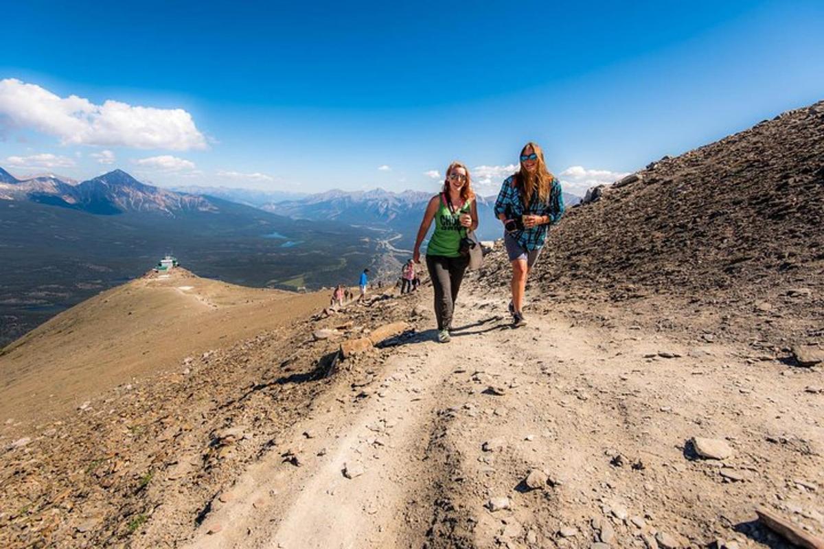 two women walking down a dirt road on a mountain