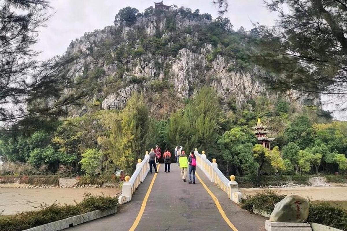 a group of people walking across a bridge in front of a mountain