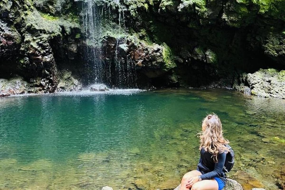 жінка сидить на скелі перед водоспадом