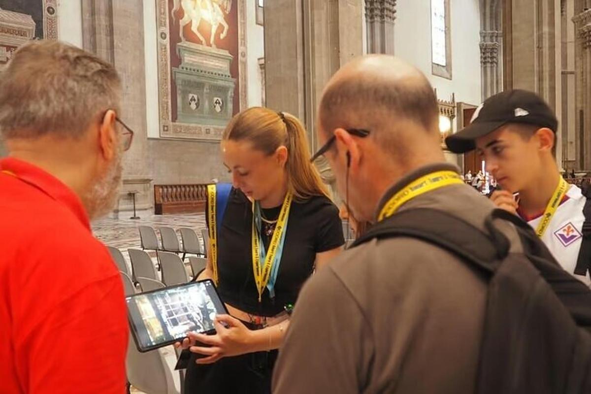 sekumpulan orang berdiri di dalam bilik melihat tablet