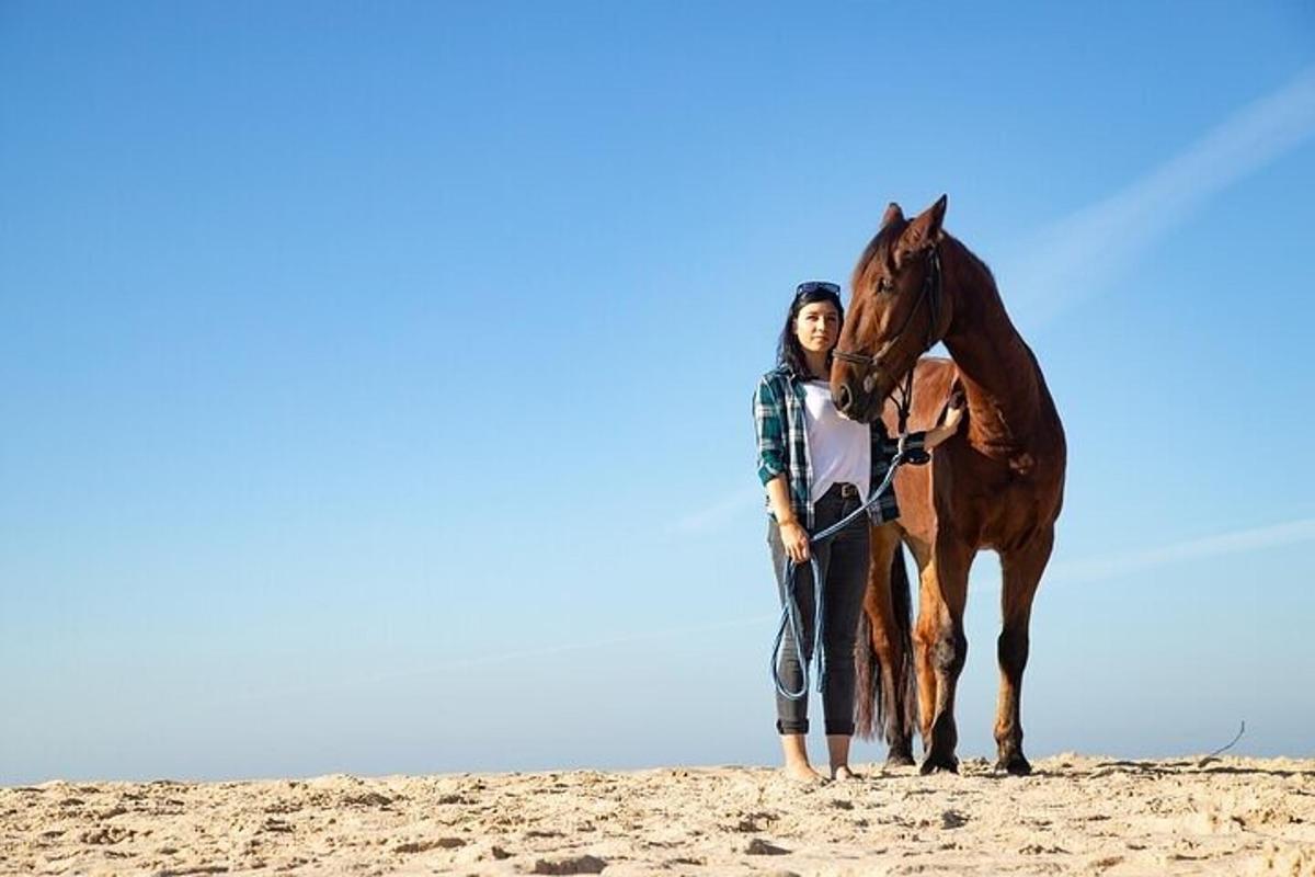 une femme debout à côté d'un cheval sur la plage