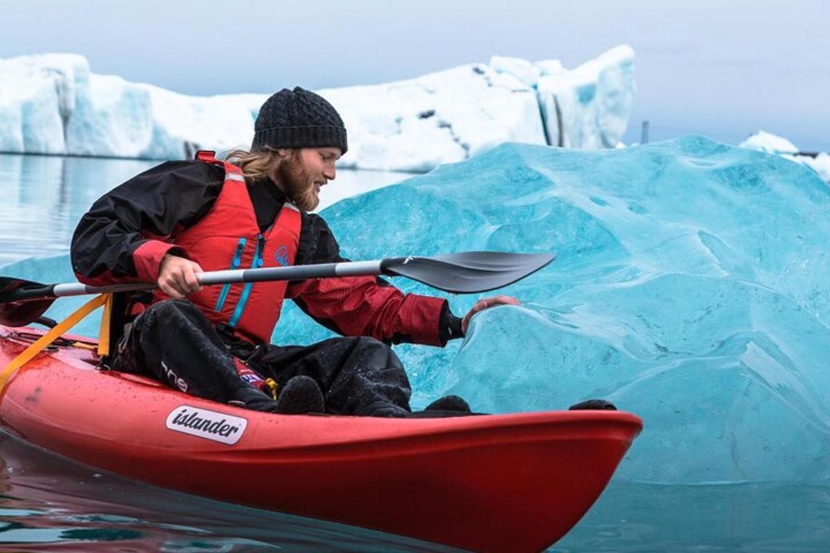 a man in a kayak in front of an iceberg