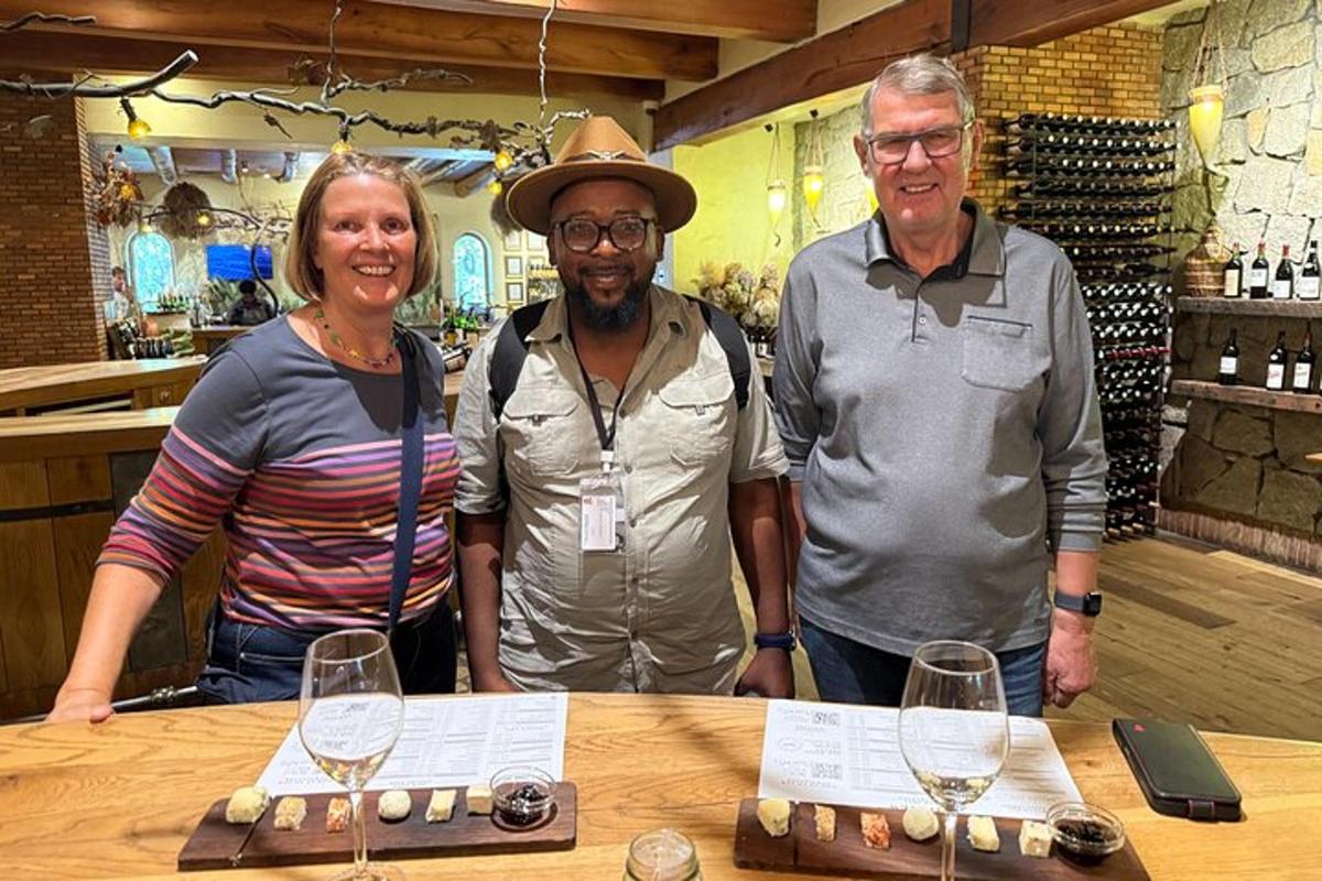 Tres personas de pie frente a una mesa con copas de vino.