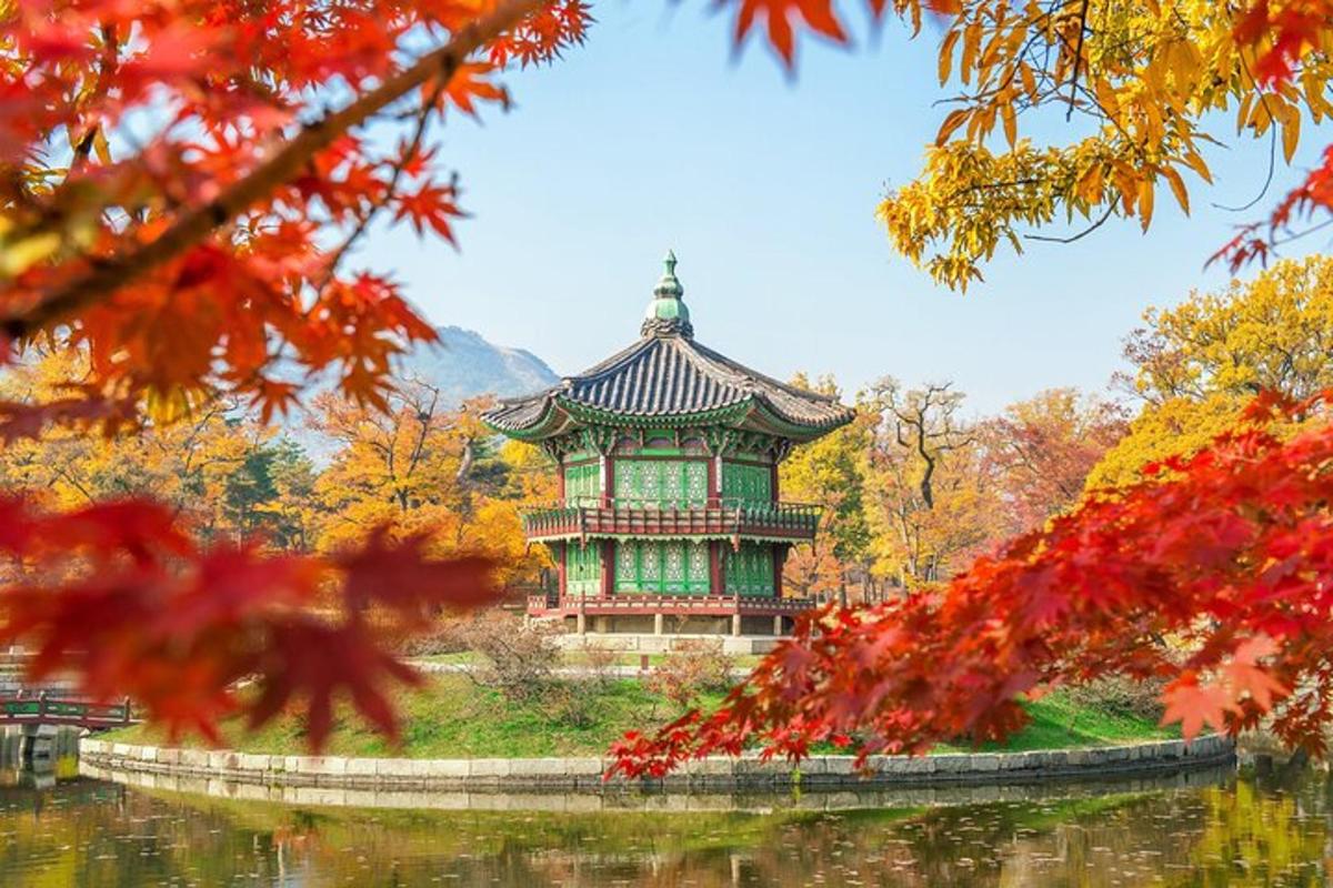 a pagoda in the middle of a lake with autumn leaves
