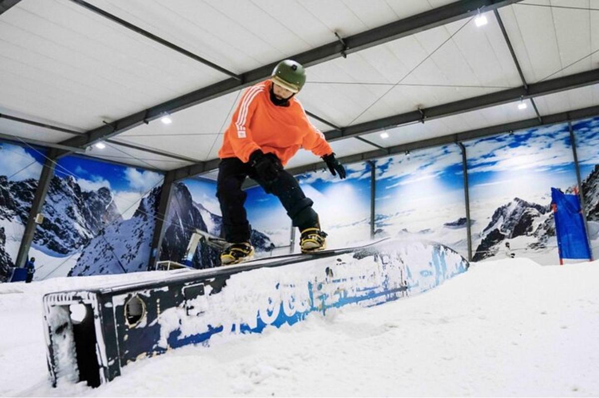 um homem andando de snowboard em um trilho na neve