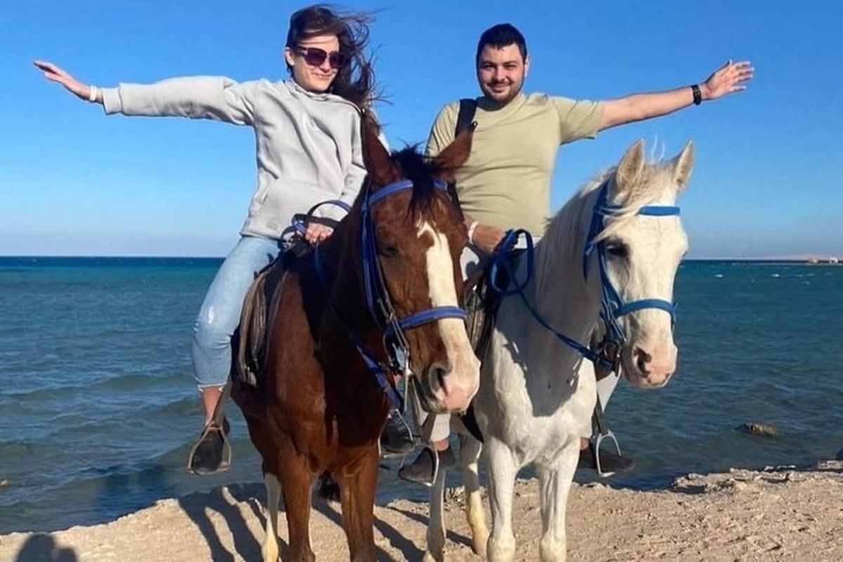 un uomo e una donna a cavallo sulla spiaggia