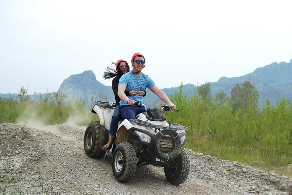 un uomo e una donna in sella a un quad su una strada sterrata