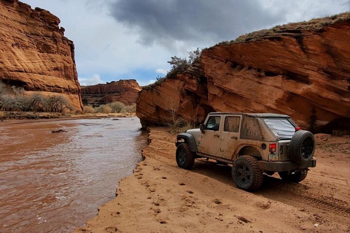 a jeep parked on the sand near a river