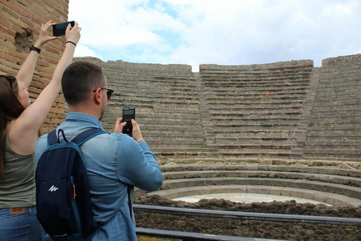 a man and woman taking pictures of an amphitheater