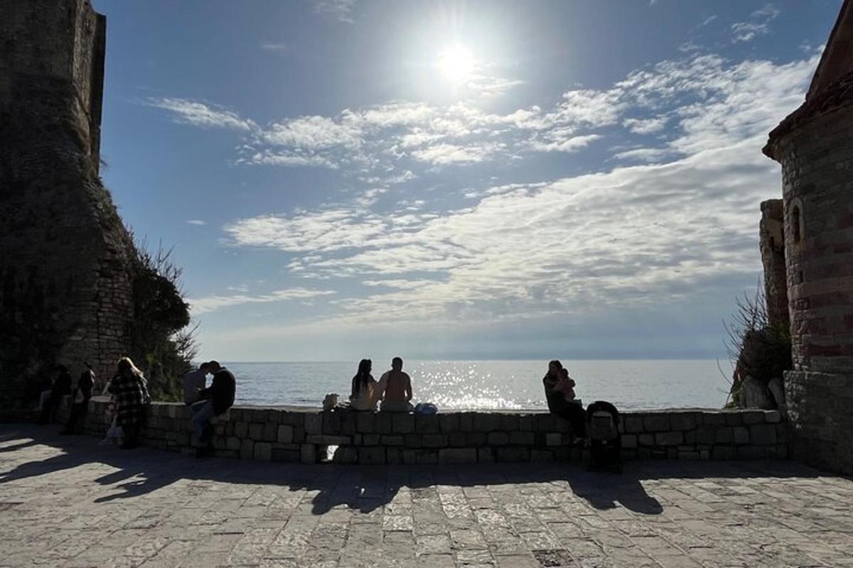 Un grupo de personas sentadas en un muro cerca del océano.