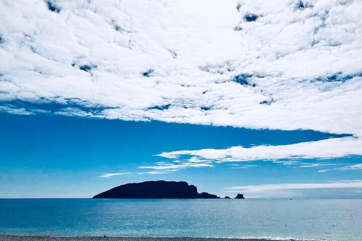 eyja í hafinu undir skýjuðum himni