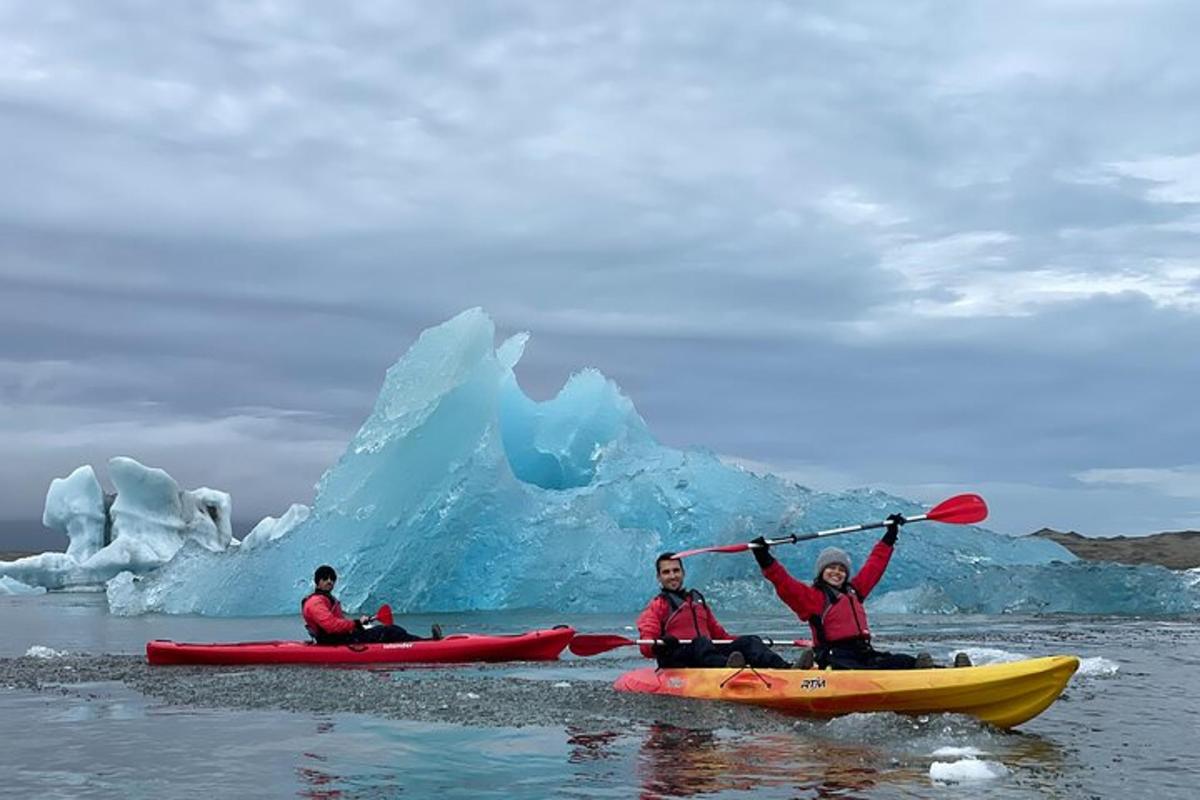 three people in kayaks in front of an iceberg