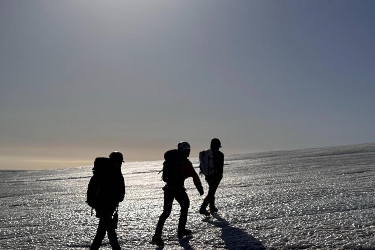 a group of three people walking across a snow covered field