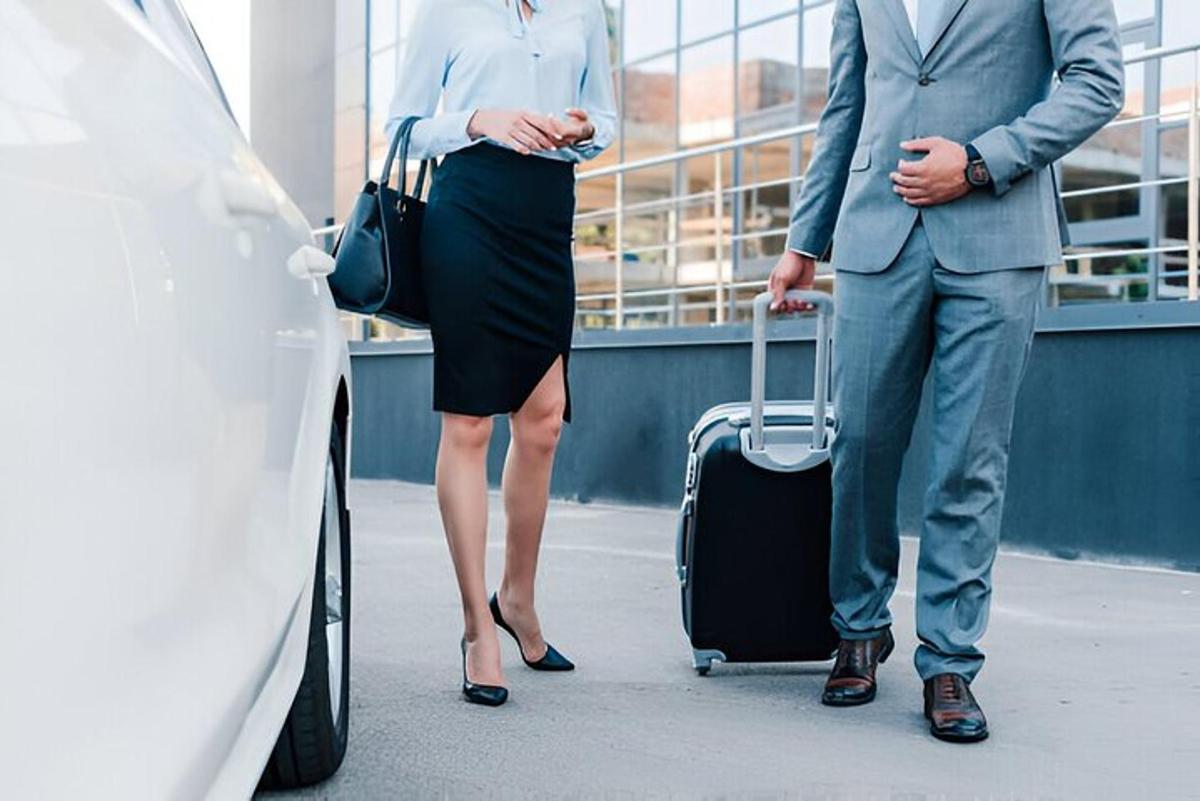 vyras ir moteris su lagaminu stovi šalia automobilių