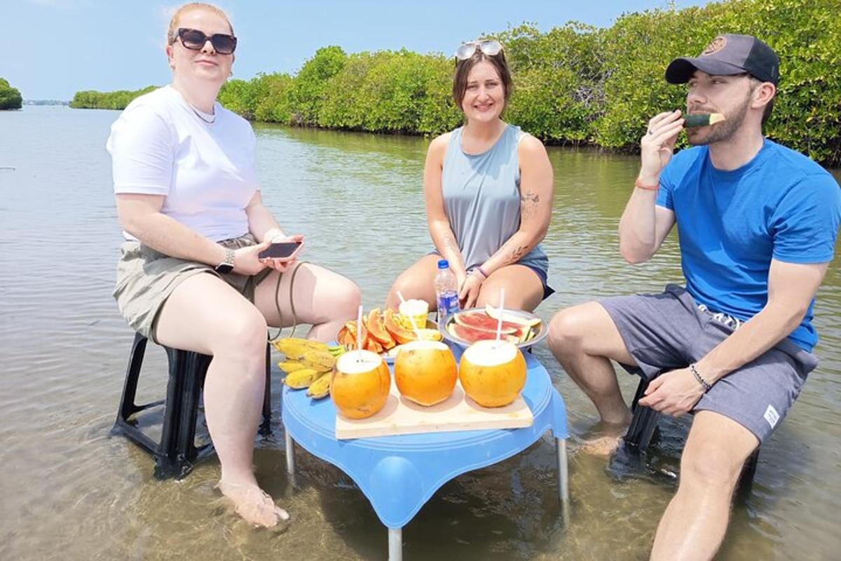 three people sitting in the water with a picnic table in the water