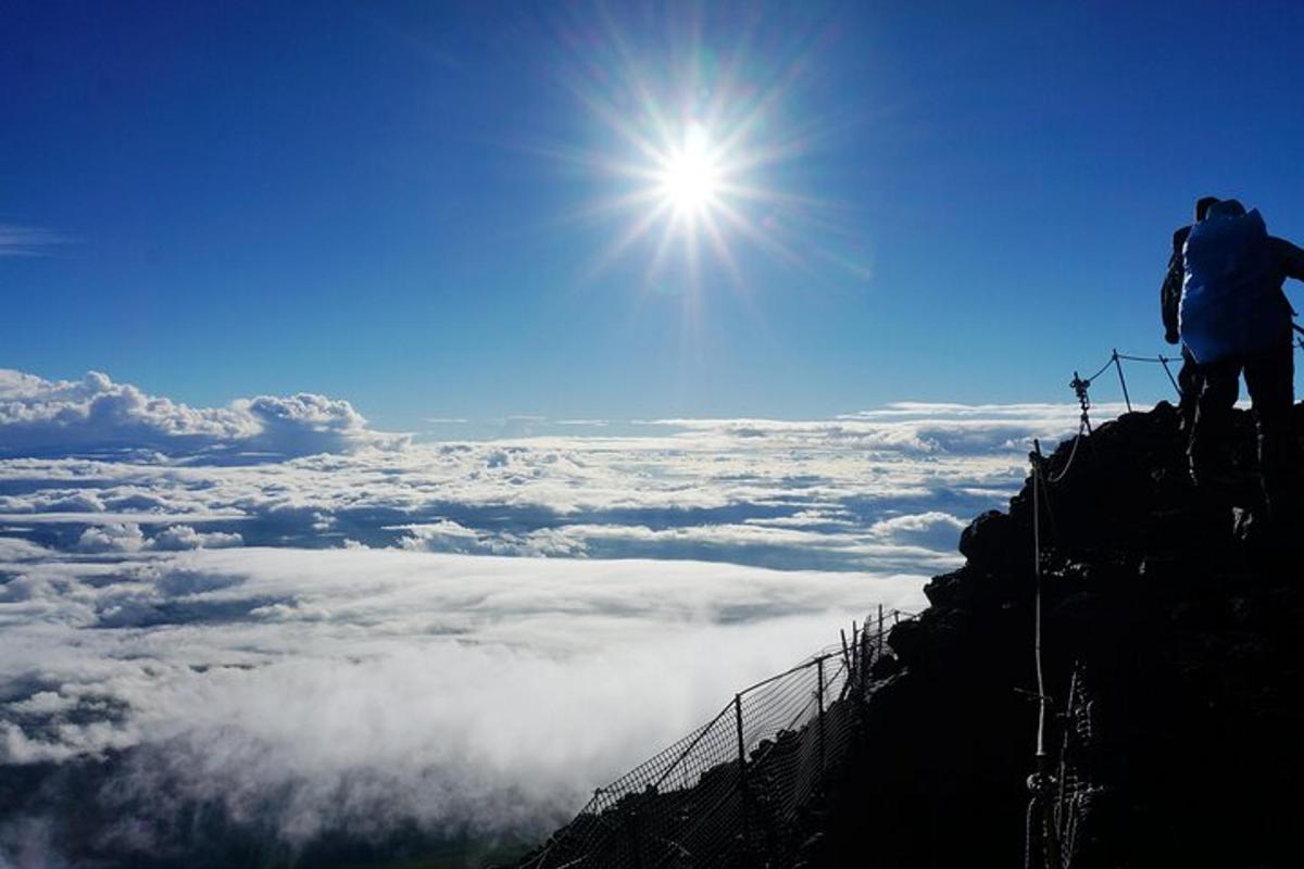 seseorang yang berdiri di atas gunung melihat ke atas awan