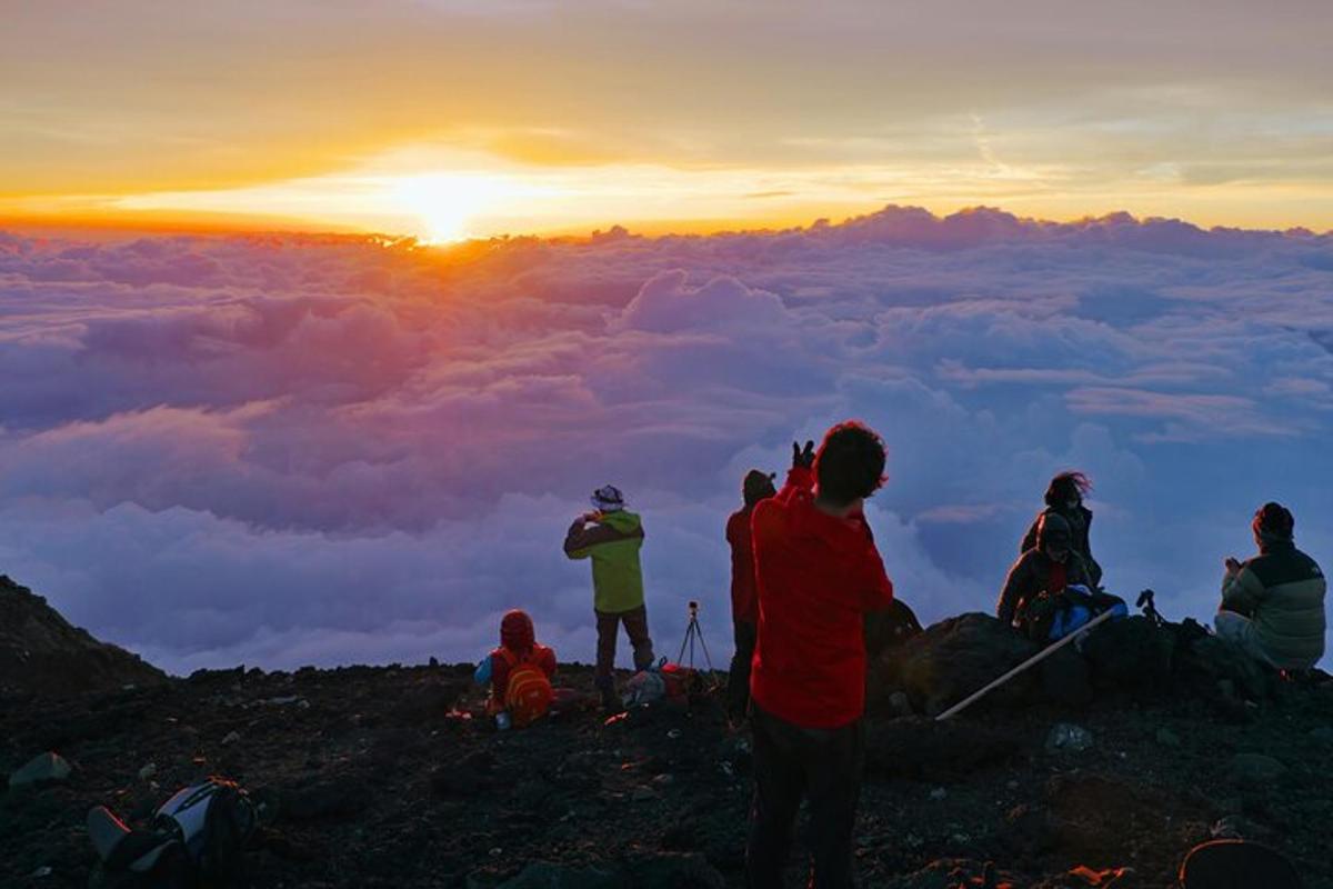un gruppo di persone sedute in cima a una montagna al tramonto