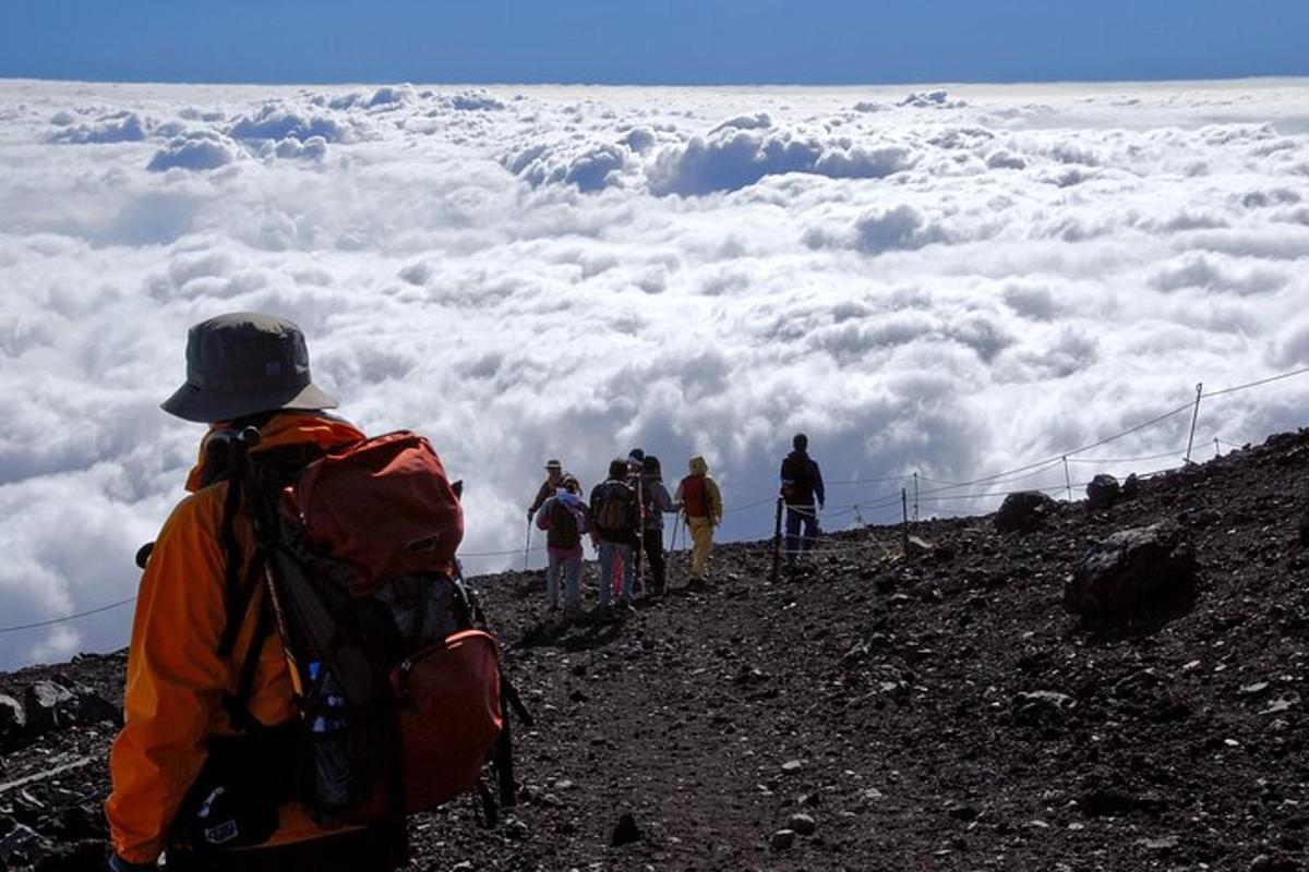 un gruppo di persone in piedi sulla cima di una montagna con nuvole