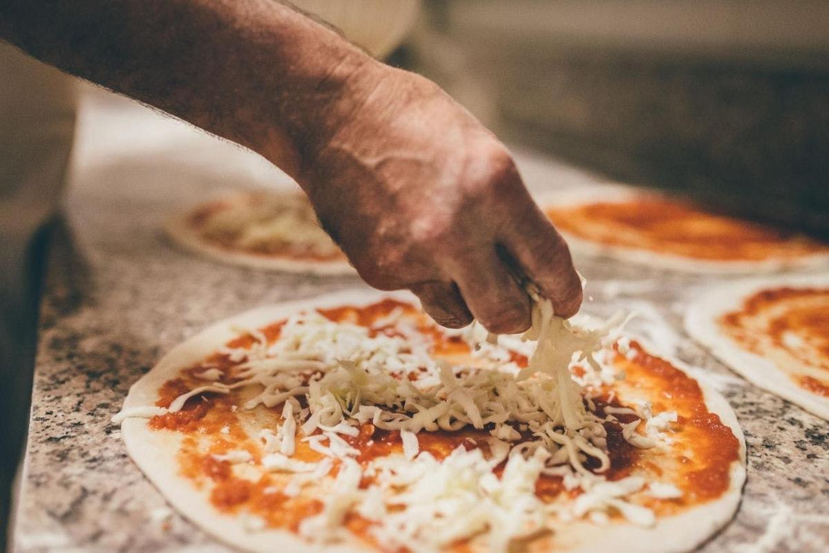 a person sprinkling cheese on top of a pizza