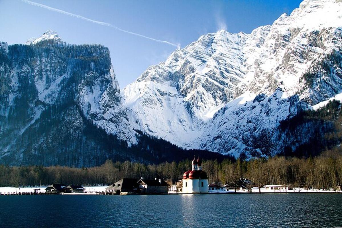 a lighthouse in the middle of a lake with a snow covered mountain
