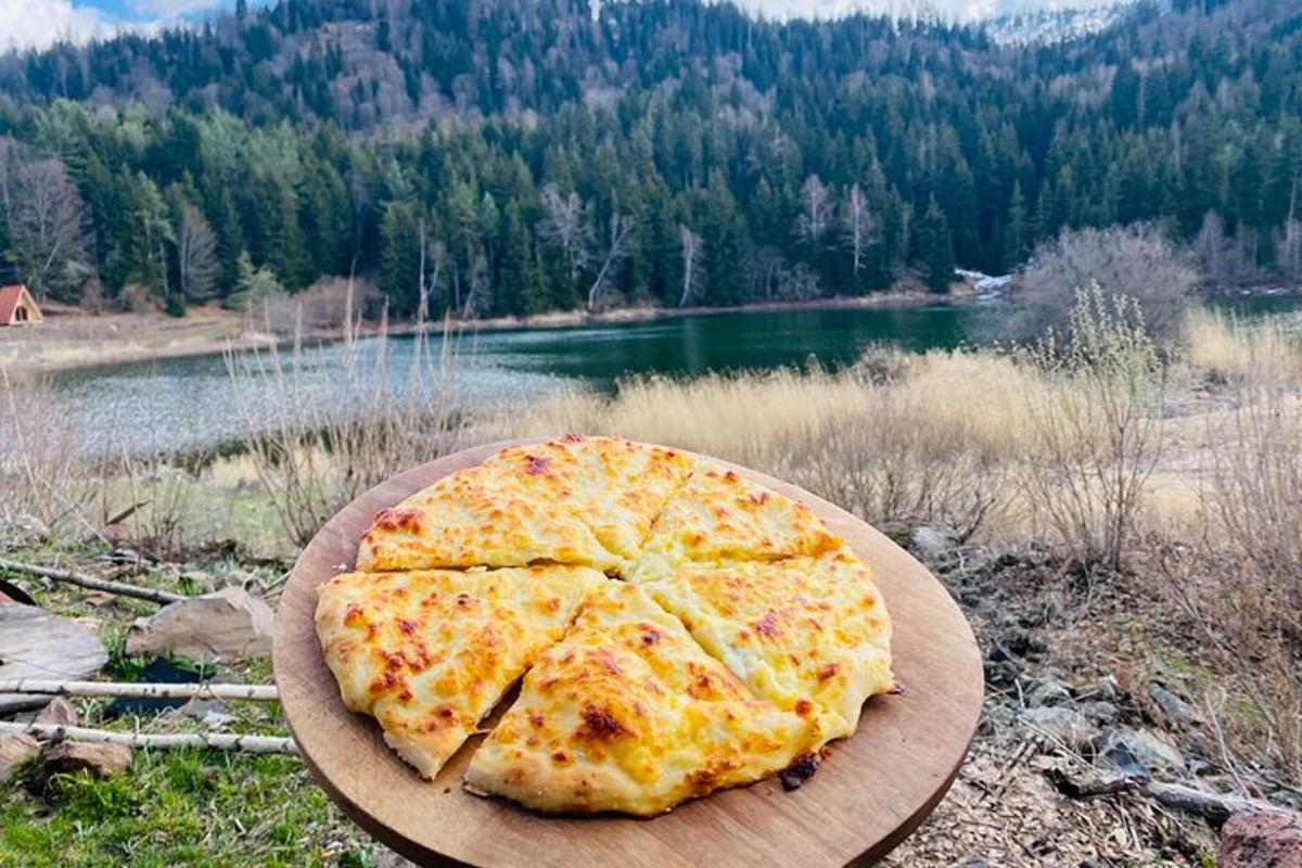 isang pizza na nakaupo sa ibabaw ng isang kahoy na plato sa tabi ng isang lawa