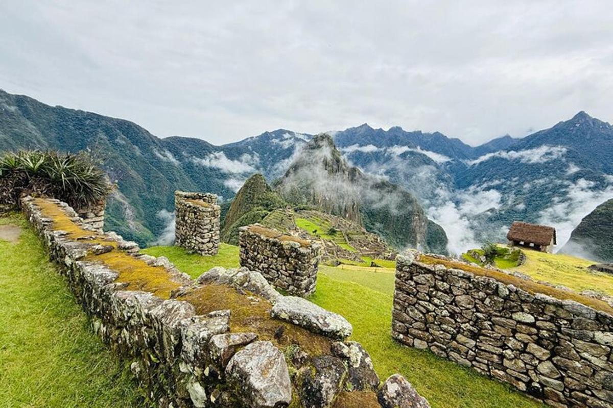 a stone wall on a field with mountains in the background