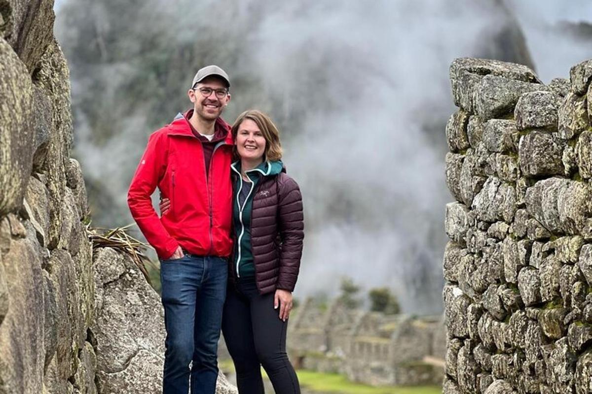 a man and woman standing next to a stone wall