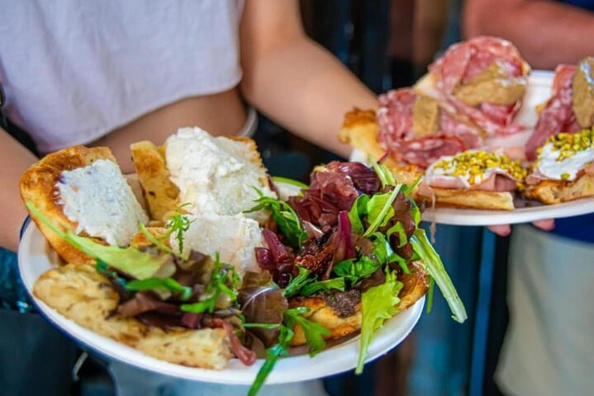 osoba držící dva talíře jídla s pizzou