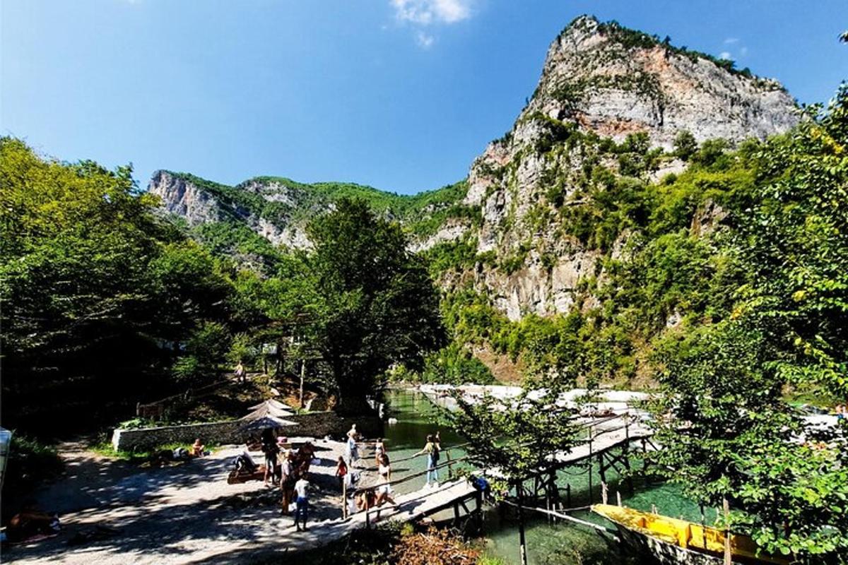 a group of people standing on a bridge near a mountain