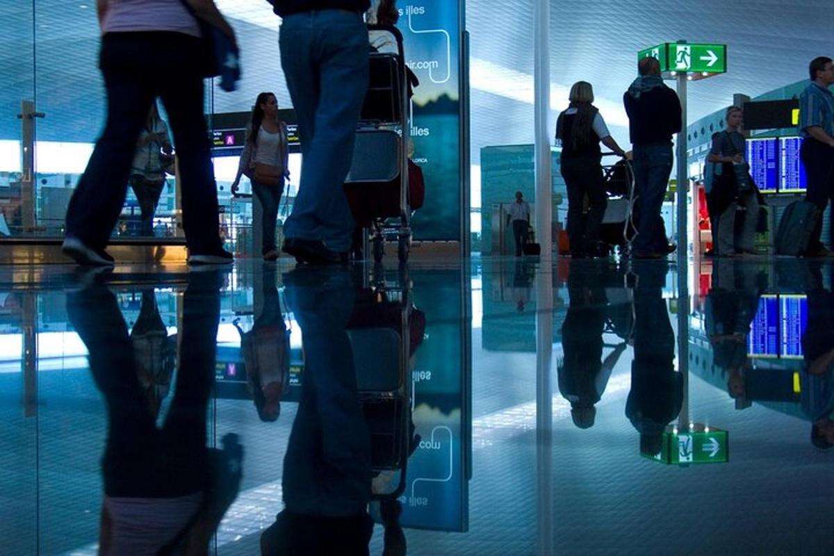 Un reflejo de gente caminando en un aeropuerto con equipaje.