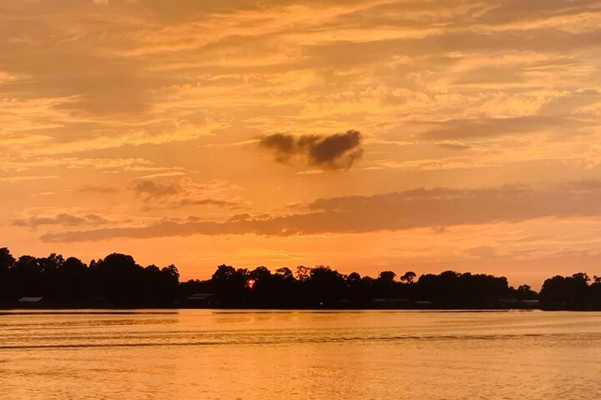 un tramonto su un fiume con alberi sullo sfondo