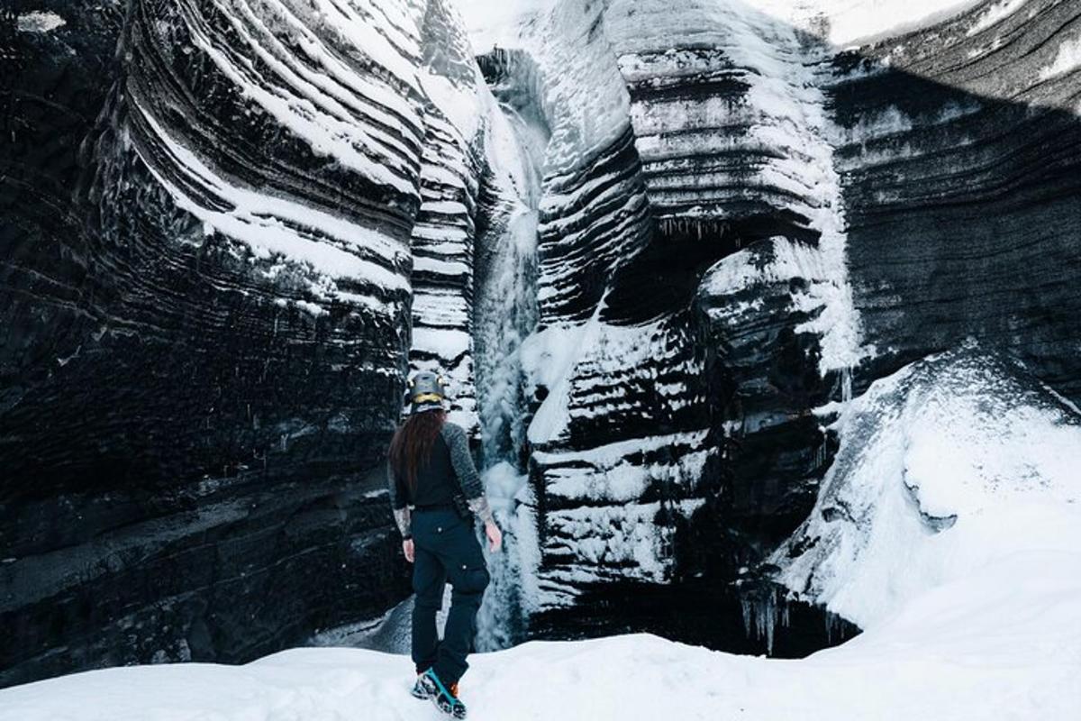 um homem parado na neve ao lado de uma cachoeira