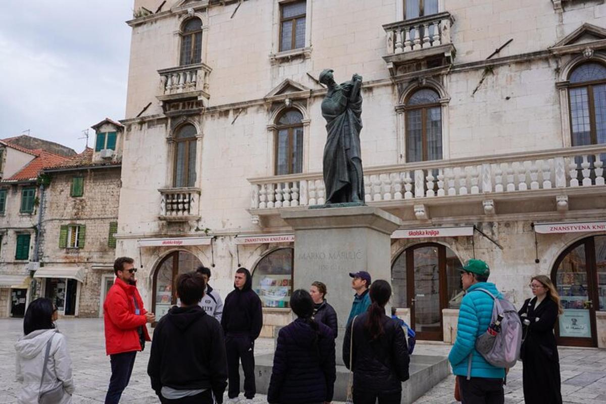 μια ομάδα ανθρώπων που στέκονται μπροστά σε ένα άγαλμα