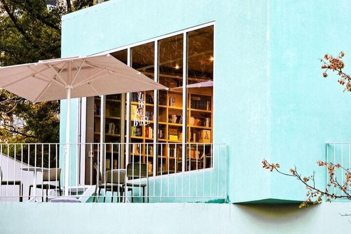 un edificio blu con un ombrellone, tavoli e sedie