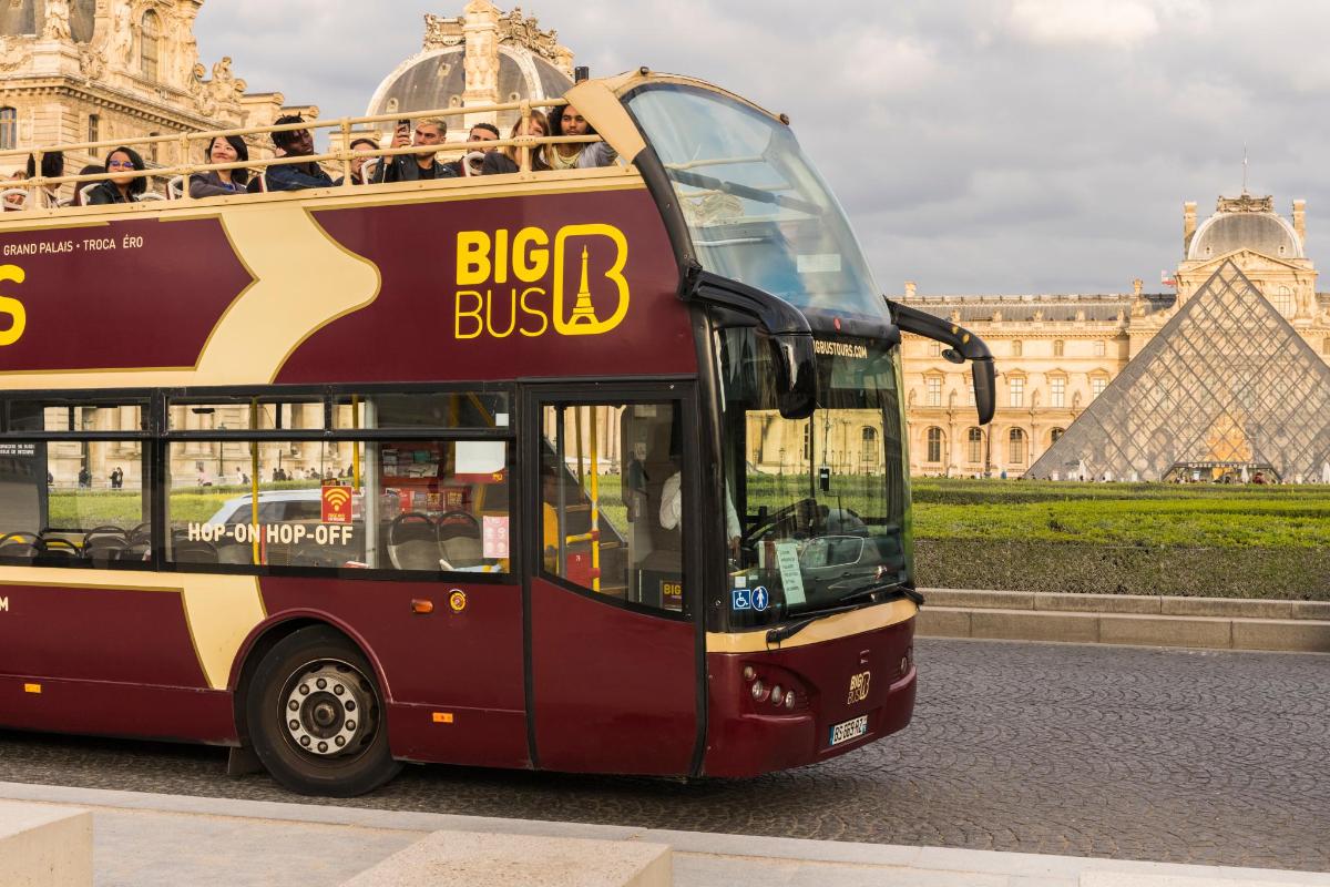 um ônibus de dois andares estacionado em frente ao Louvre