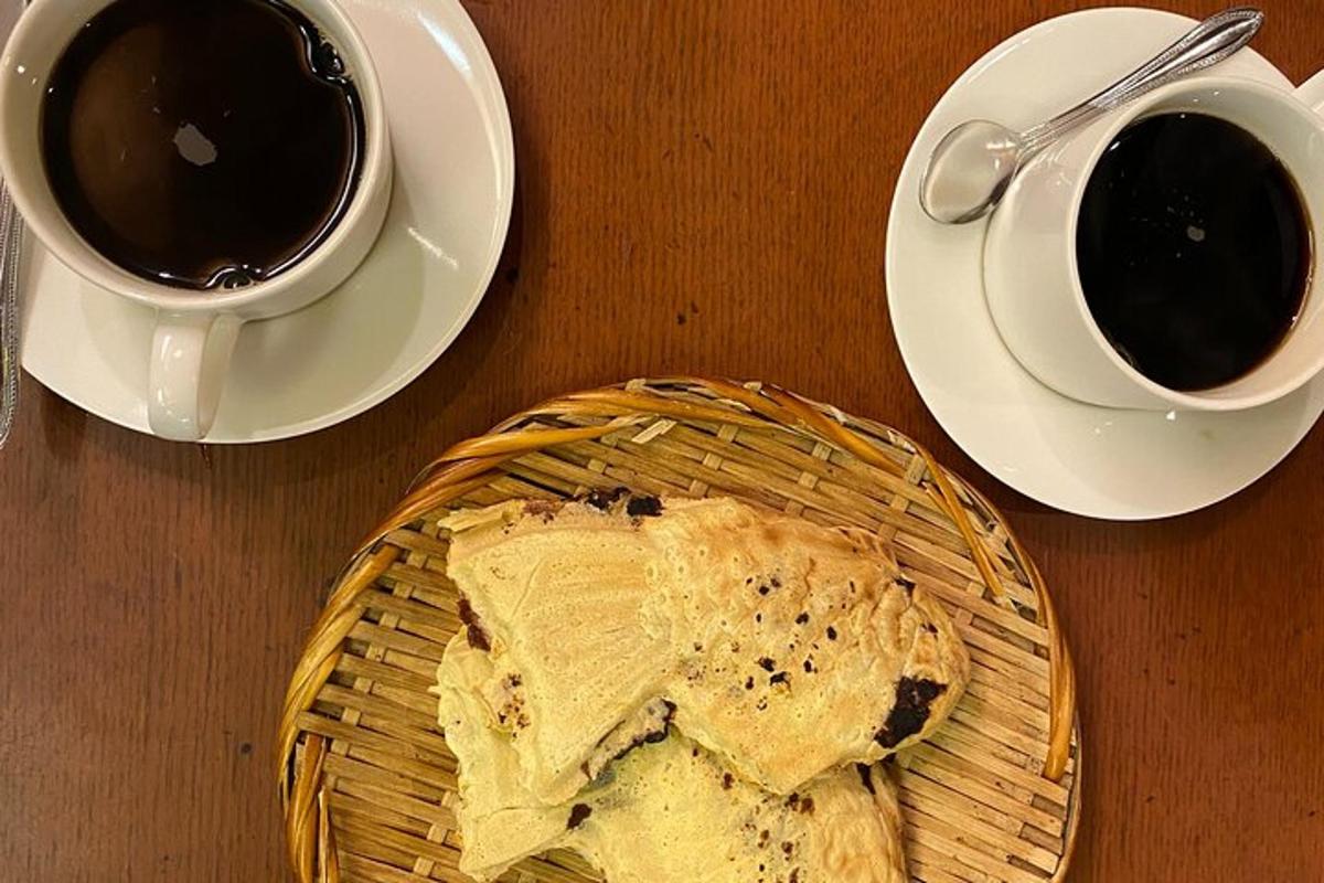 a table with a plate of bread and two cups of coffee