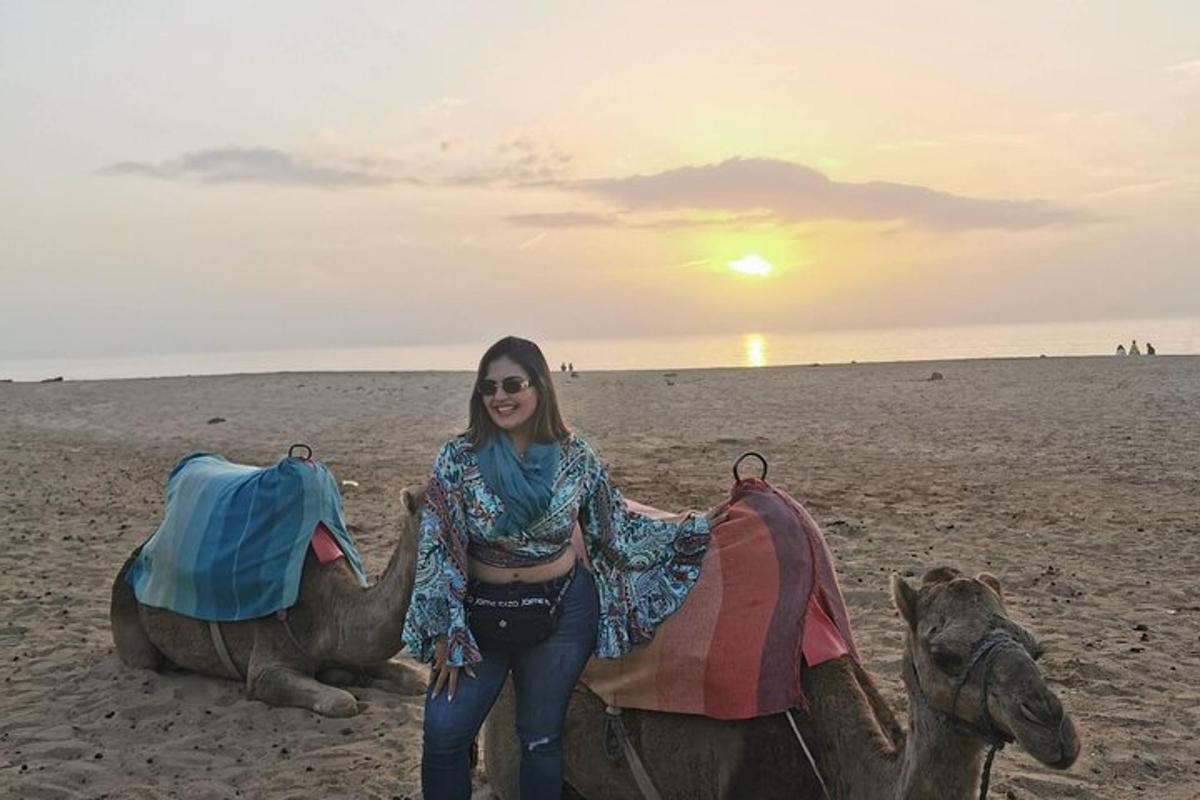 una donna in piedi accanto a un cammello sulla spiaggia