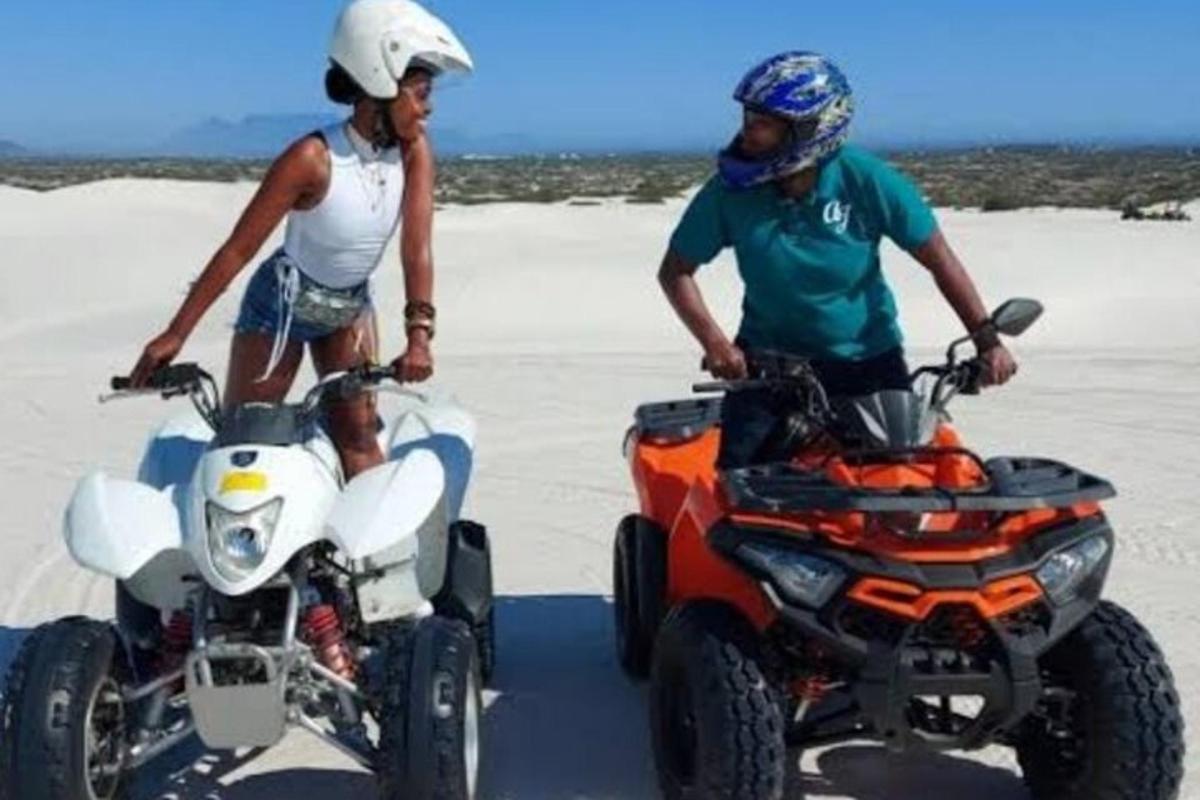 moški in ženska, ki stojita na štirikolesnikih na plaži