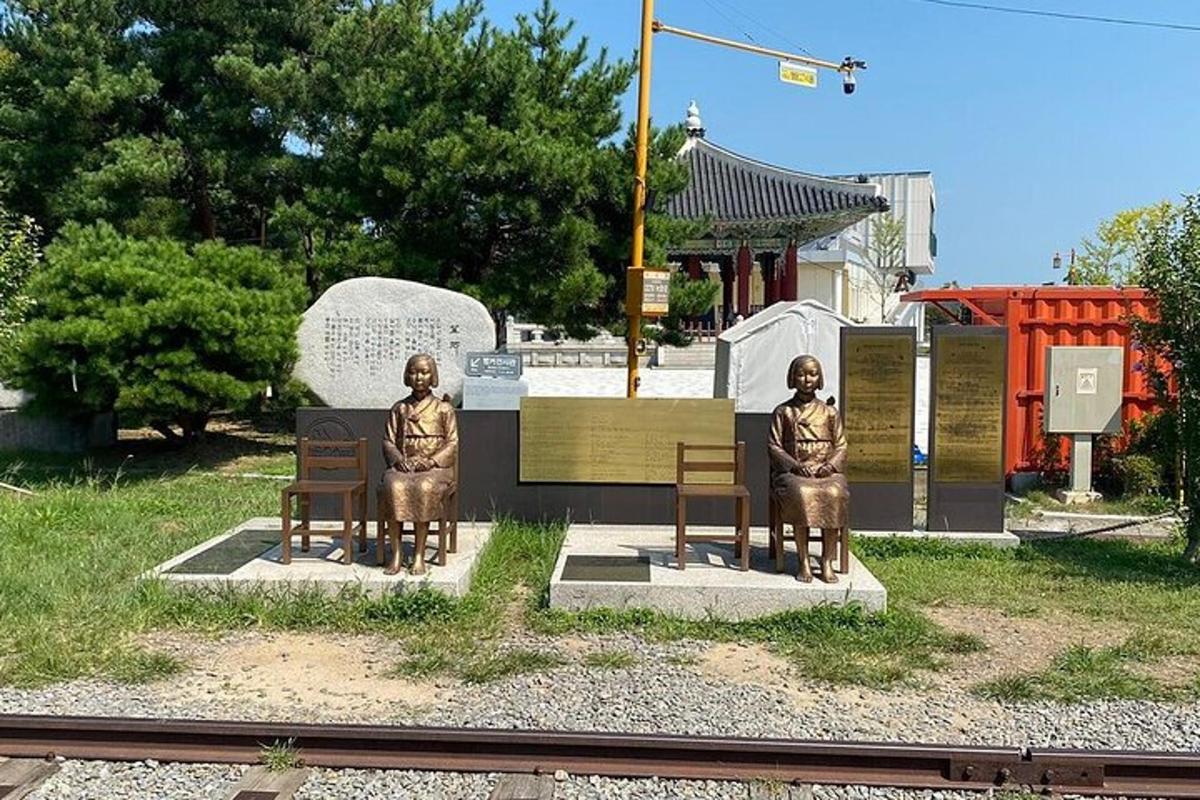 zwei Statuen von Männern, die auf Bänken an einem Bahnhof sitzen
