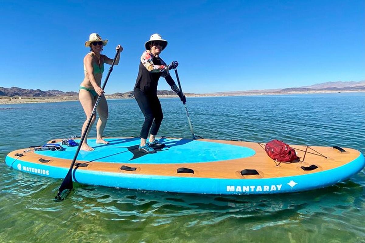two women are standing on a paddle board in the water