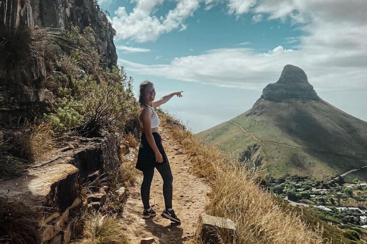 Una mujer parada en una montaña con el brazo extendido.