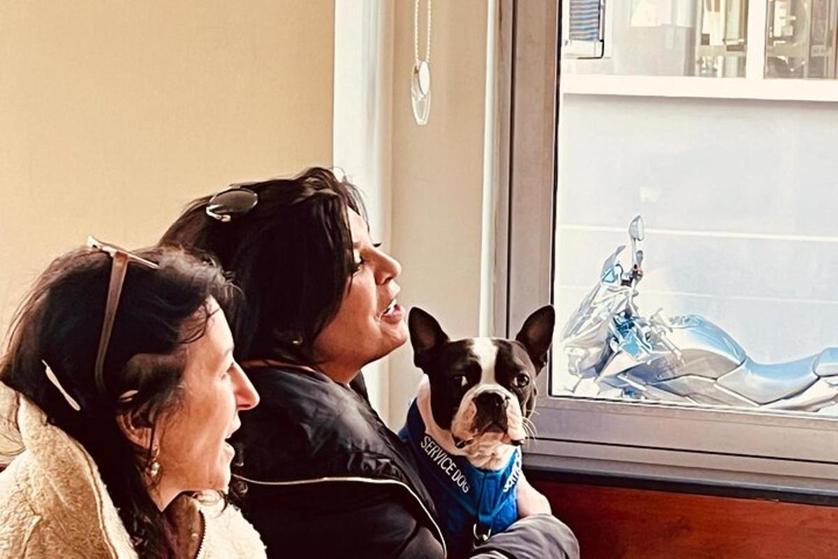 due donne e un cane guardano fuori da una finestra