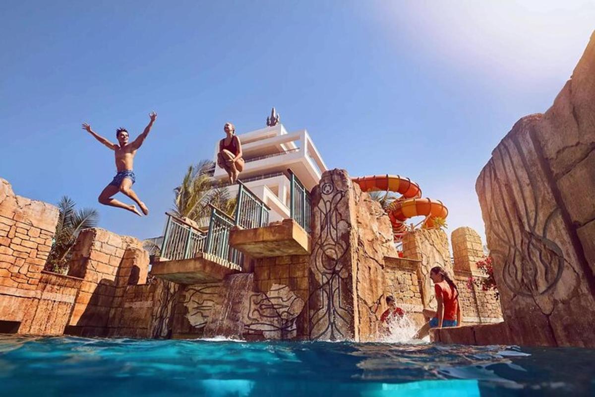 a group of people jumping into the water at a water park